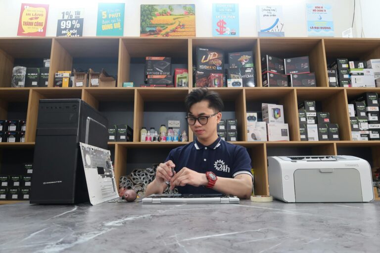 Young technician fixing a computer in a modern electronics store setting.